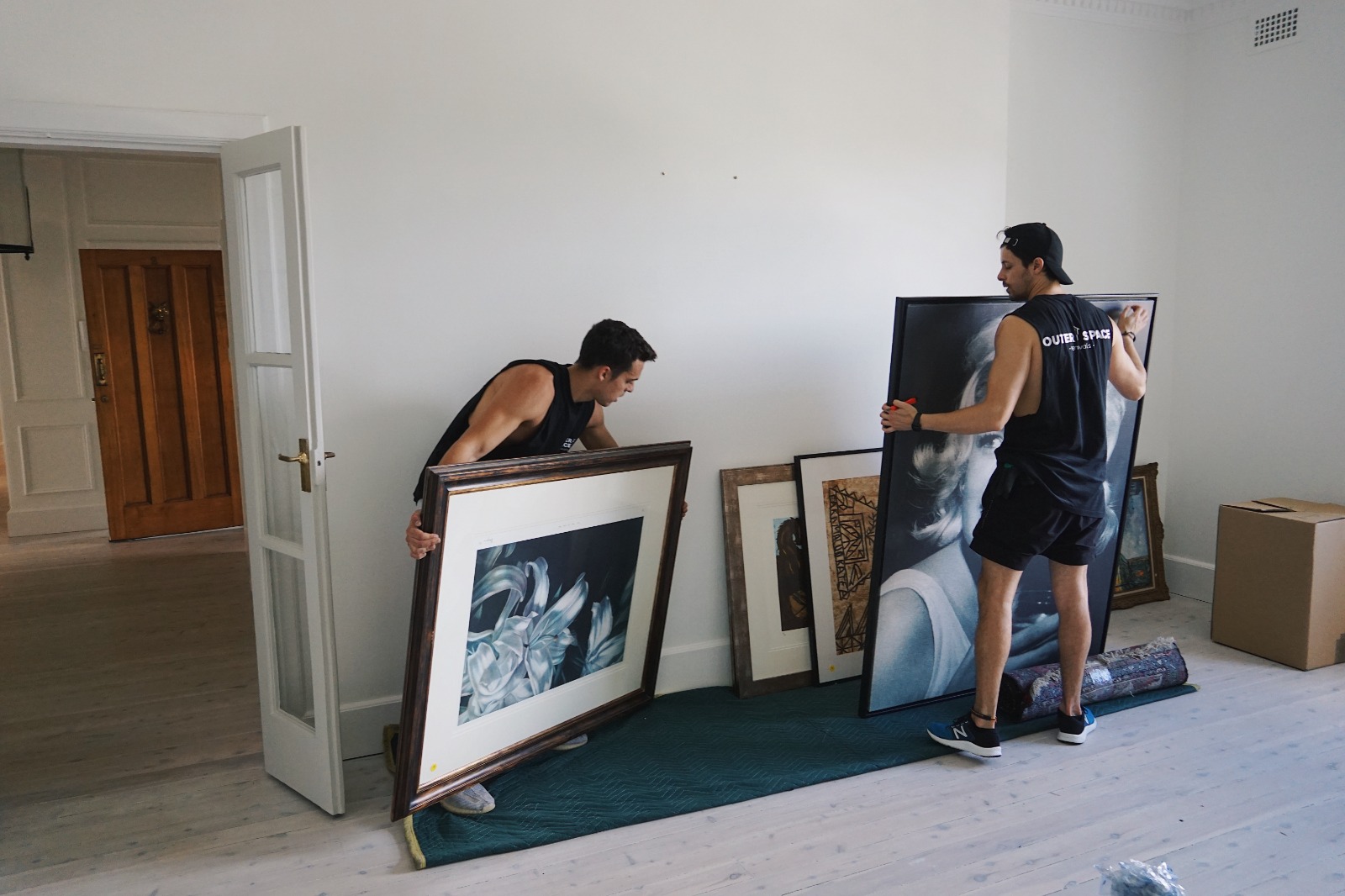 Outer Space Removals movers carrying wrapped artwork