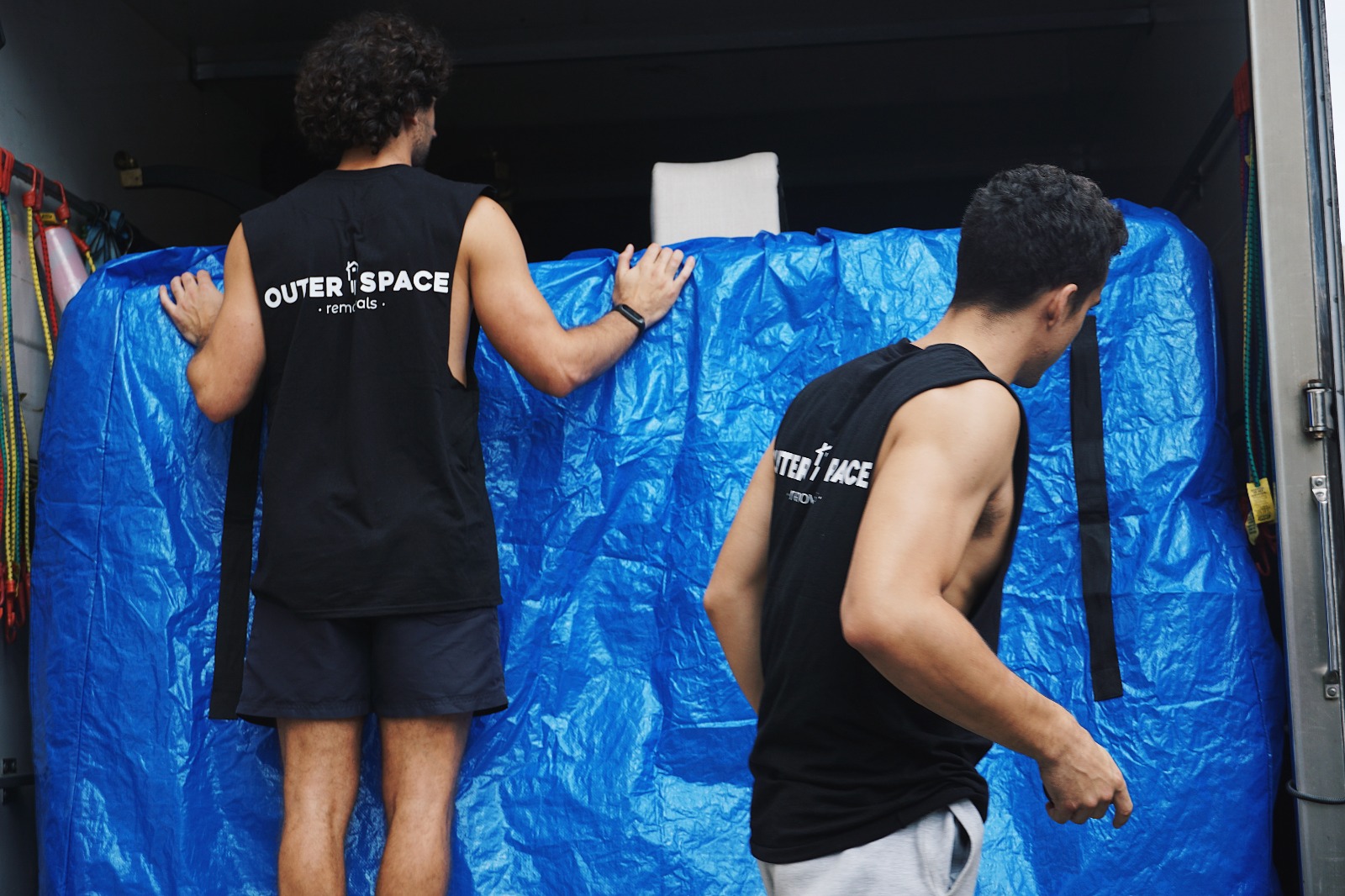Outer Space Removals movers securing wrapped furniture in the truck